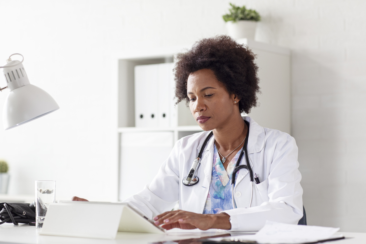 Doctor woman typing on tablet